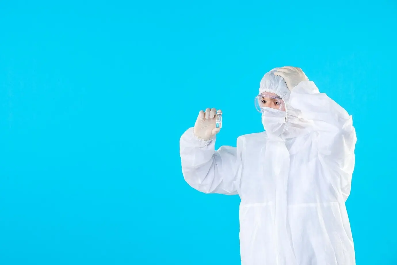 Вид спереди врача-мужчины в защитном костюме и маске на синем фоне.