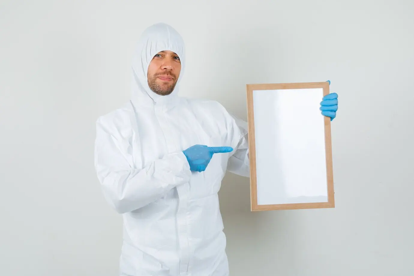 Врач-мужчина в защитном костюме указывает на пустую рамку.